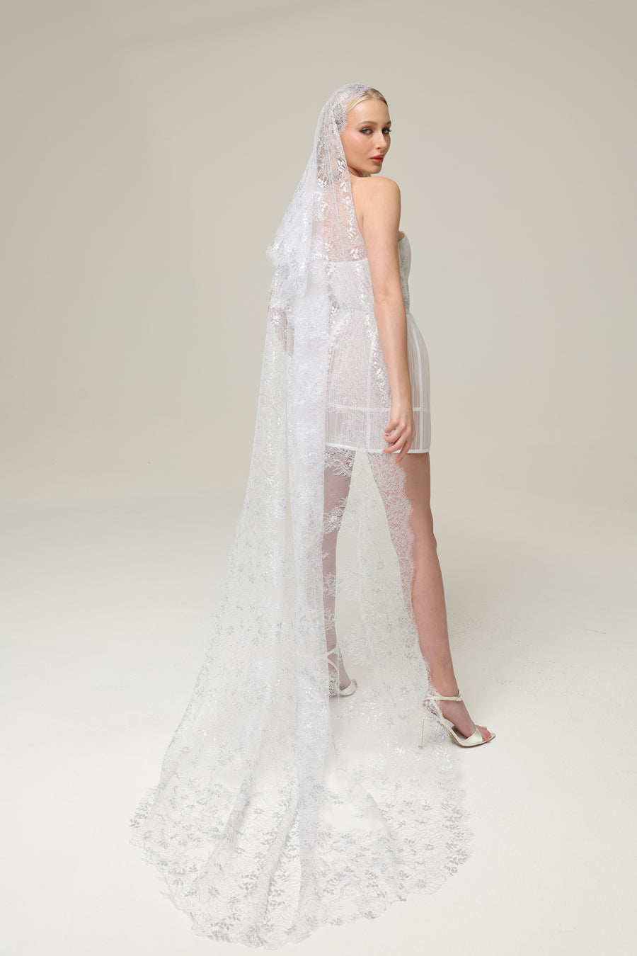 Back profile of Amara’s Glow Bridal Mini Dress. Lace Chantilly veil rented separately. 